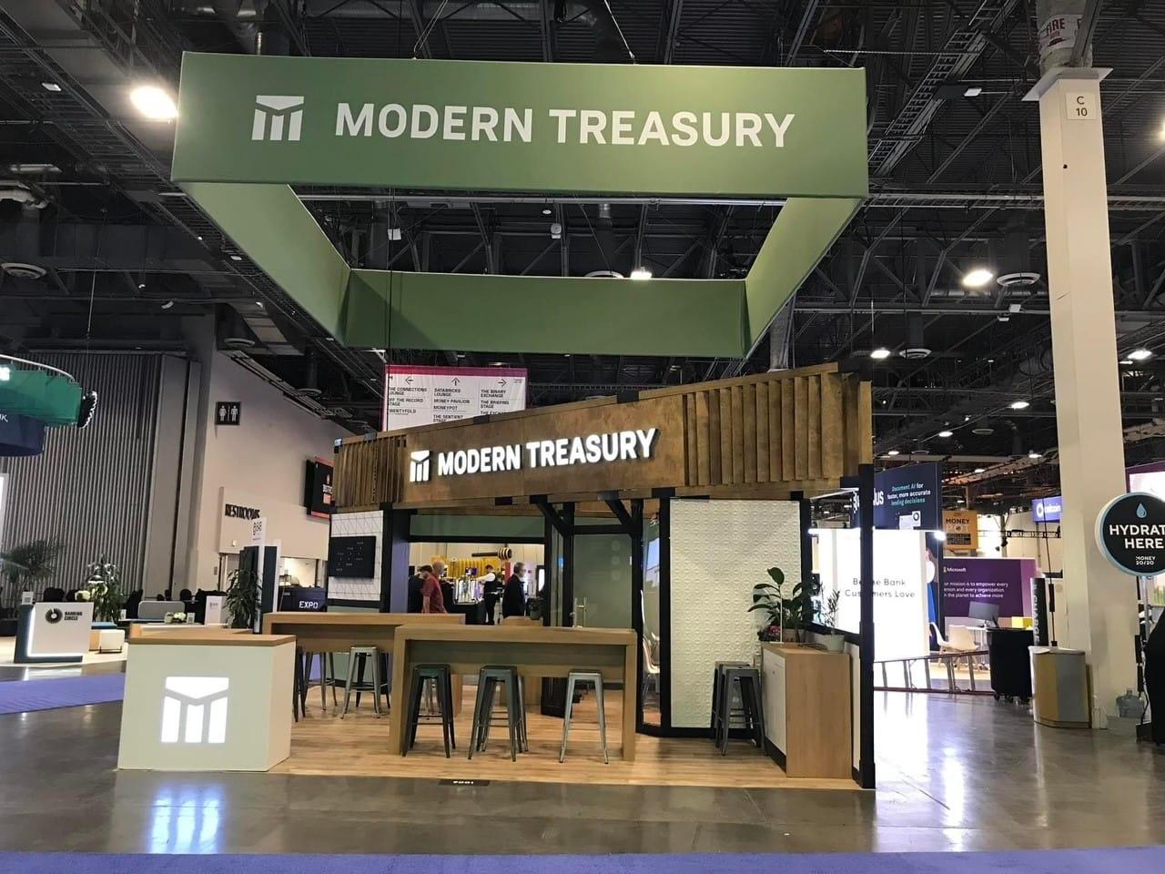 Modern Treasury booth at a trade show with green and wood accents.